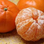 Close-up of fresh clementines and a peeled segment on a textured background.