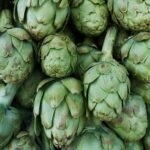 Close-up of fresh green artichokes stacked in abundance at a local market.